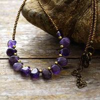 A purple Amethyst and seed bead necklace laid out on a natural background. ALLORA JADE