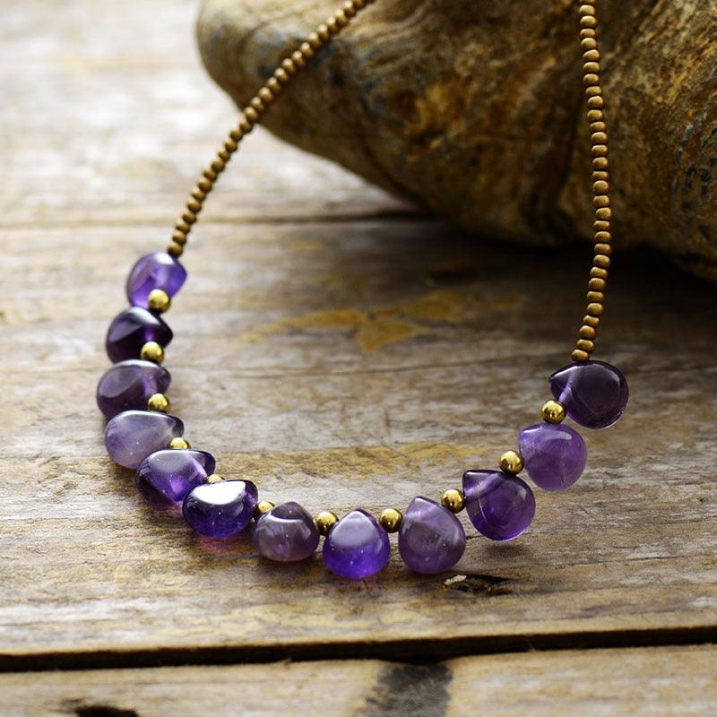 A purple Amethyst and seed bead necklace laid out on a wooden surface. ALLORA JADE