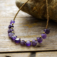A purple Amethyst and seed bead necklace laid out on a wooden surface. ALLORA JADE