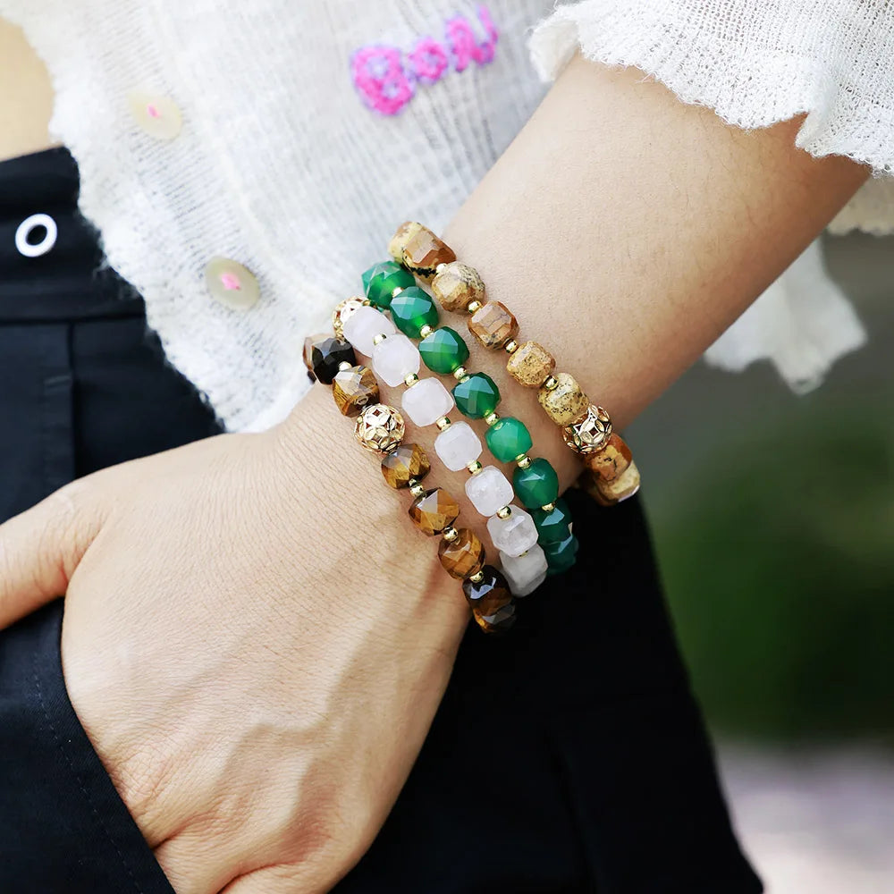 Close-up of a wrist wearing multiple beaded bracelets with a blurred background. Faceted Cube Bracelet | ALLORA JADE