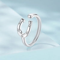 Silver horseshoe-shaped ring with small stones on a light blue background