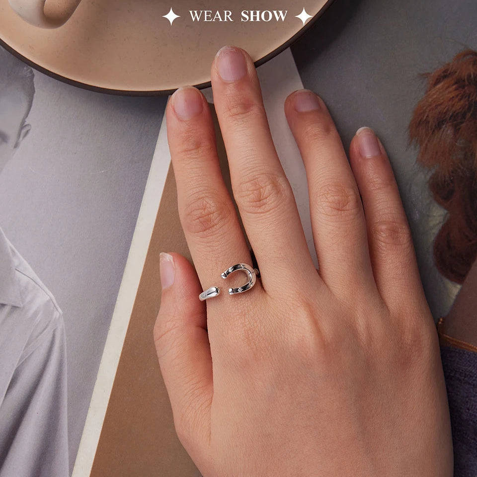 Hand wearing a silver horseshoe ring with a blurred background