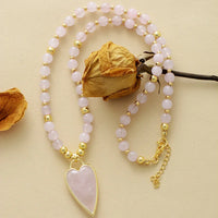 Rose Quartz beaded necklace with a Rose Quartz heart-shaped pendant on a beige background