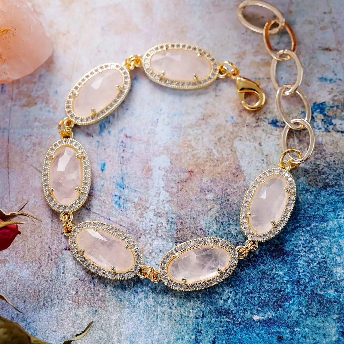 Gold bracelet with Rose Quartz stones on a textured surface