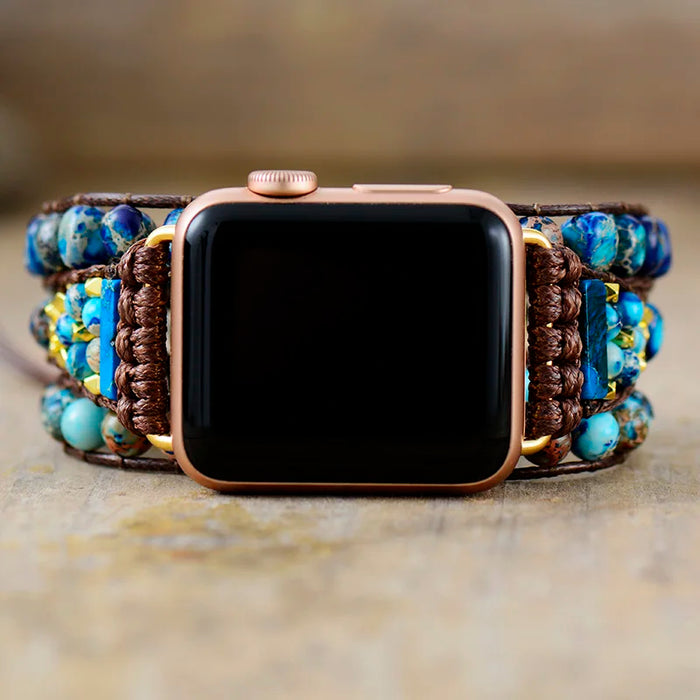 Smartwatch with a decorative band featuring blue and brown beads on a neutral background