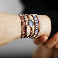 Close-up of a wrist wearing multiple bracelets with beads and and Labradorite charm.