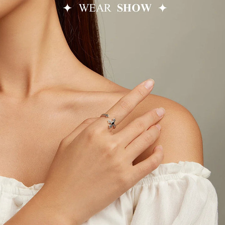 Close-up of a hand wearing a ring with a cross design on a neutral background.