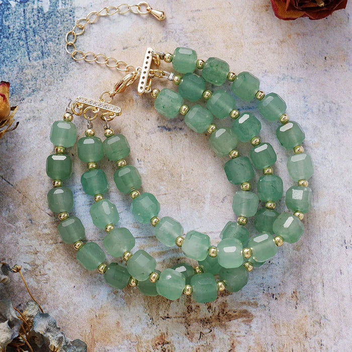 Green beaded bracelet with gold accents on a textured surface