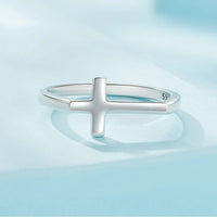 Silver ring with a cross design on a light blue background