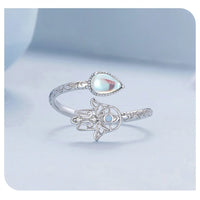 Silver ring with Hamsa hand design and gemstone on a light blue background
