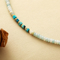 Necklace with turquoise and gold beads on a beige background