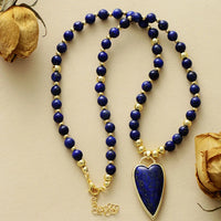 Lapis Lazuli beaded necklace with a Lapis Lazuli heart-shaped pendant on a beige background