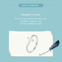 Silver cross ring on a piece of paper with a feather, against a light blue background.