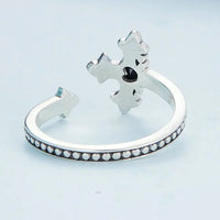 Display of a Cross silver ring from the back and underside on a light blue background.