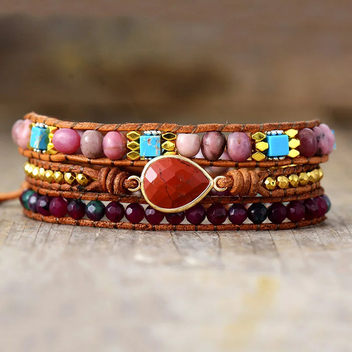 Multicolored beaded bracelet with a Red central stone, displayed on a wooden surface