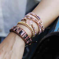 Close-up of a wrist wearing multiple colorful and pink beaded bracelets with a blurred background