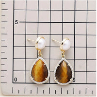 Tiger's Eye Pavé Teardrop Dangle Earrings featuring brown gemstone drops framed by sparkling rhinestones, with imitation pearl studs in gold-coloured settings on a scale background to show sizing.