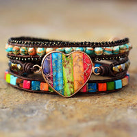 Multicolored beaded bracelet with a heart-shaped charm on a stone surface