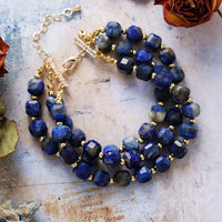 Three strand Lapis Lazuli beaded bracelets on a textured surface with flowers.