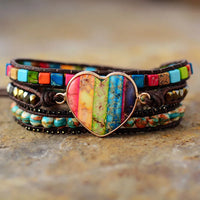 Multicolored beaded bracelet with a heart-shaped charm on a textured surface