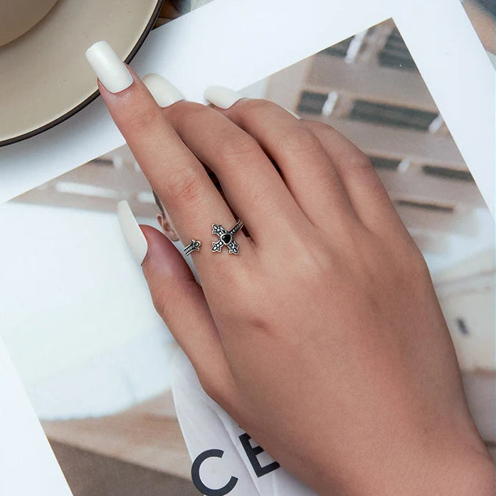 Hand wearing a silver ring with cross design on a magazine background