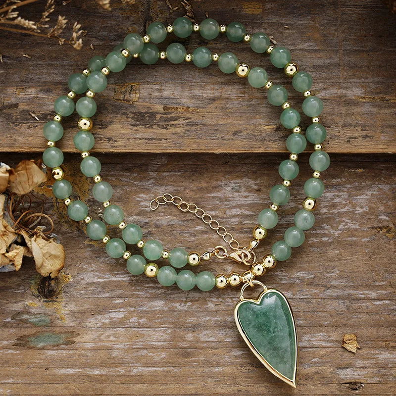 Green Aventurine beaded necklace with a Green Aventurine heart-shaped pendant on a wooden surface