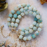 Stack of turquoise beaded bracelets with gold accents on a textured surface