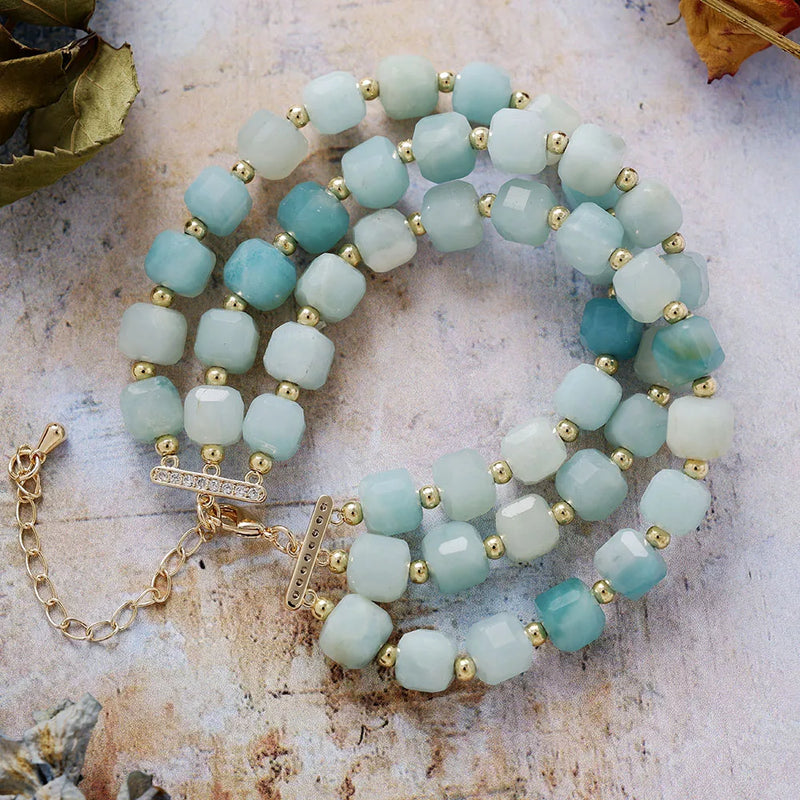 Stack of turquoise beaded bracelets with gold accents on a textured surface
