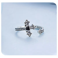 Adjustable silver ring with cross and heart design on a light blue background