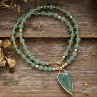 Green Aventurine beaded necklace with a Green Aventurine heart-shaped pendant on a wooden surface