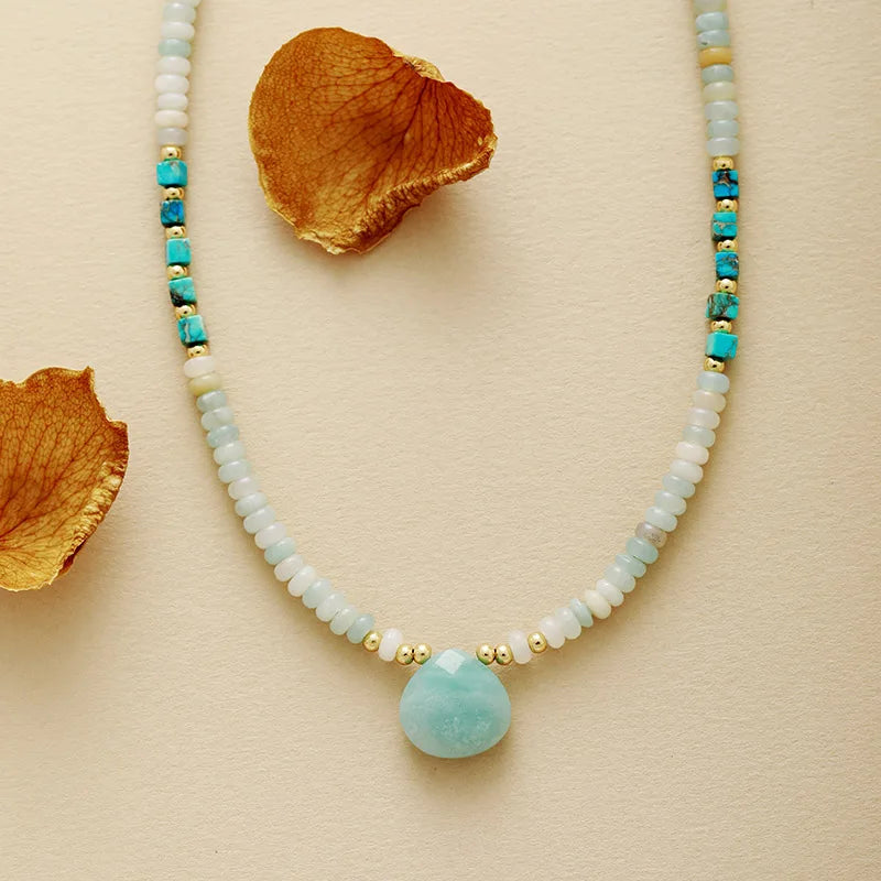 Necklace with Amazonite pendant and gold accents on a beige background