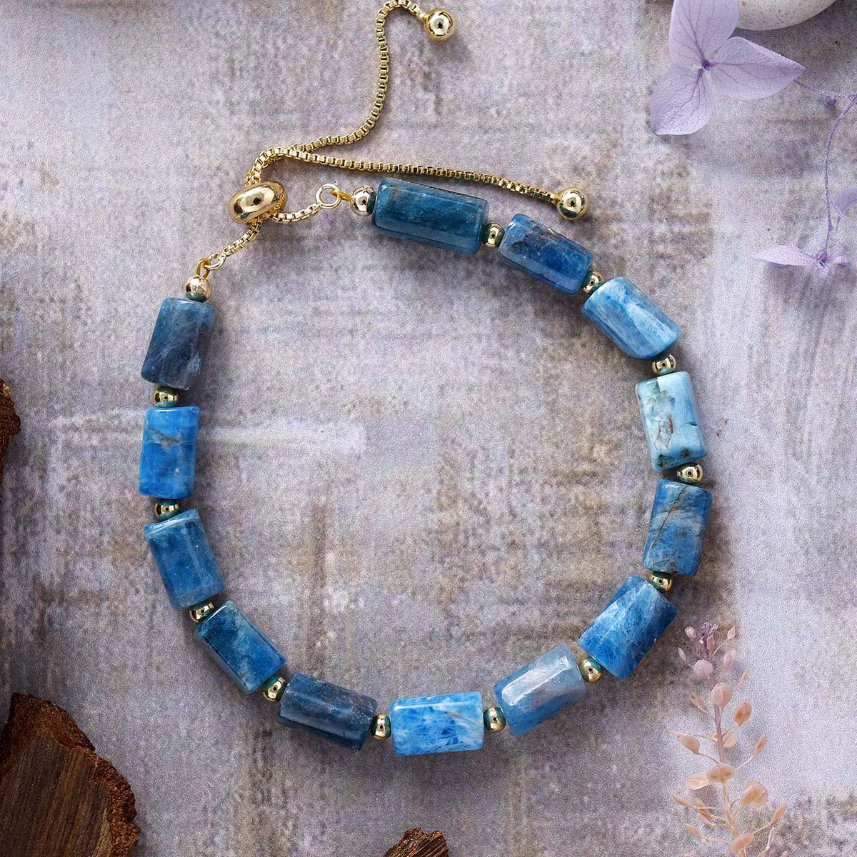 Blue beaded bracelet with gold accents on a textured surface
