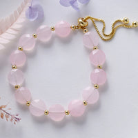 Pink beaded bracelet with gold accents on a light background