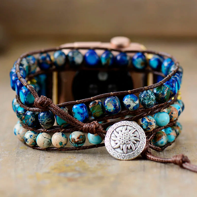 Multistrand watch band with blue beads and a decorative button on a neutral background
