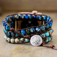 Multistrand watch band with blue beads and a decorative button on a neutral background