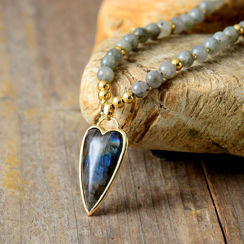 Necklace with a heart-shaped labradorite pendant on a stone surface