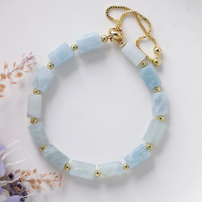 Bracelet with light blue beads and gold accents on a white background