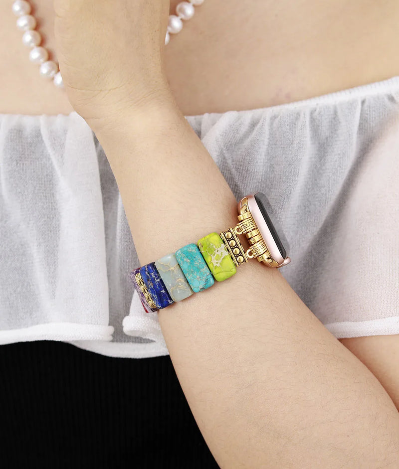 Multicolored beaded bracelet on a wrist with a white top and black background. 7 Chakras Jasper Stretchy Apple Watch Band | ALLORA JADE