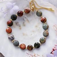 Multicolored beaded bracelet on a marble surface with decorative flowers.