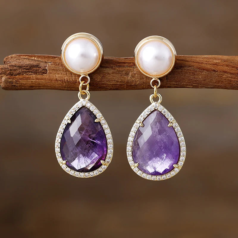 Amethyst Pavé Teardrop Dangle Earrings featuring purple gemstone drops framed by sparkling rhinestones, with imitation pearl studs in gold-coloured settings.