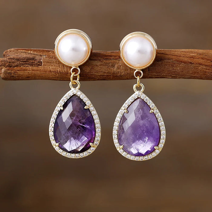 Amethyst Pavé Teardrop Dangle Earrings featuring purple gemstone drops framed by sparkling rhinestones, with imitation pearl studs in gold-coloured settings.