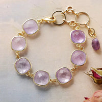 Gold bracelet with pink gemstones on a light background