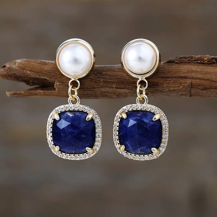 Sodalite Pavé Cushion Dangle Earrings featuring blue gemstone drops framed by sparkling rhinestones, with imitation pearl studs in gold-coloured settings.