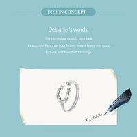 Silver horseshoe-shaped bracelet on a white card with a feather on a light blue background.