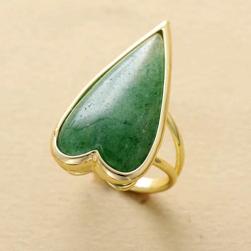 Gold ring with a heart-shaped Green Aventurine gemstone on a beige background