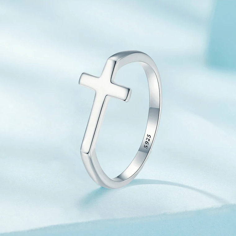 Silver cross ring on a light blue background with '925' stamp
