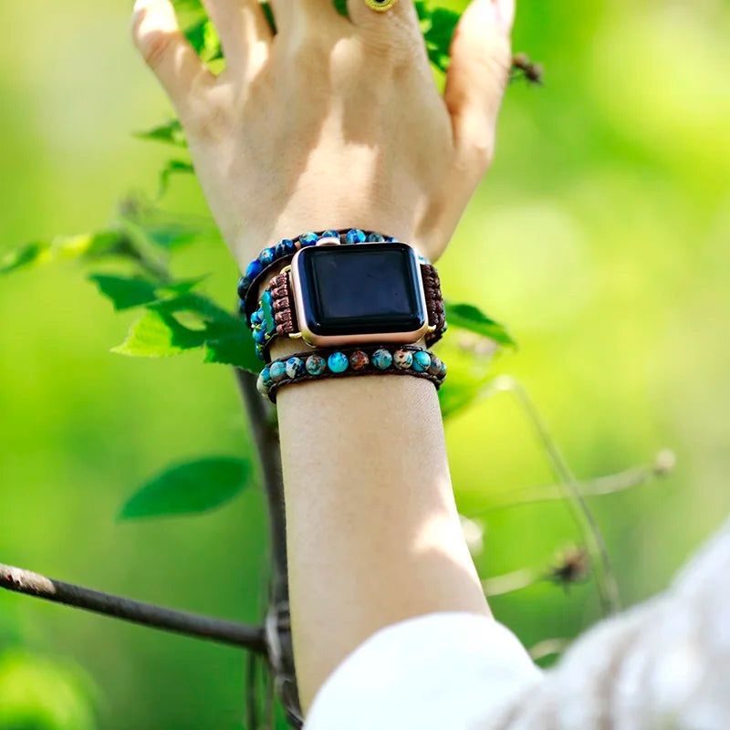 Smartwatch with a decorative band on a wrist against a green natural background