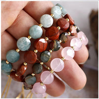 Person holding various beaded bracelets with different coloured beads.