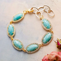 Gold bracelet with turquoise stones on a light background